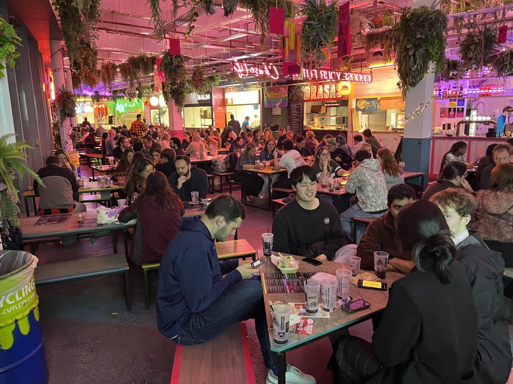 Teams playing Premier SpeedQuizzing at Edinburgh Street Food, with tables full of players under the hall's neon lights and hanging plants